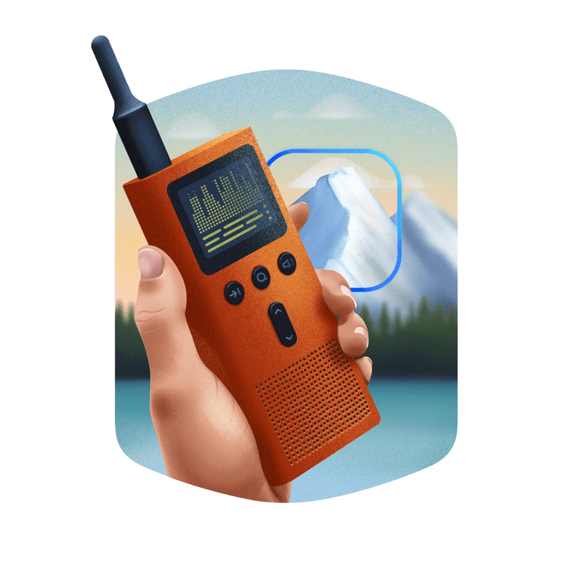 a hand holding a radio transmitter in front of a vast mountain